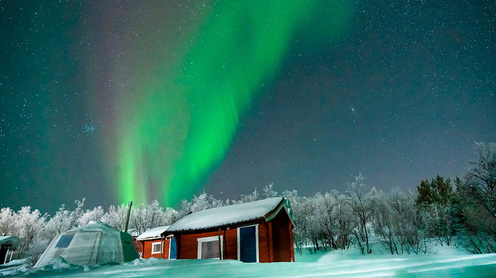 Northern Lights above hut at night in Alta, Norway